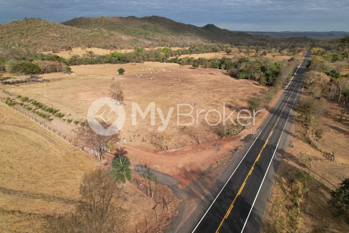 Rodovia asfaltada margeando a fazenda, com morros ao fundo, em Israelândia
